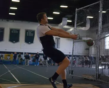 Mike winding up a throw in the indoor cage for the University of New Hampshire