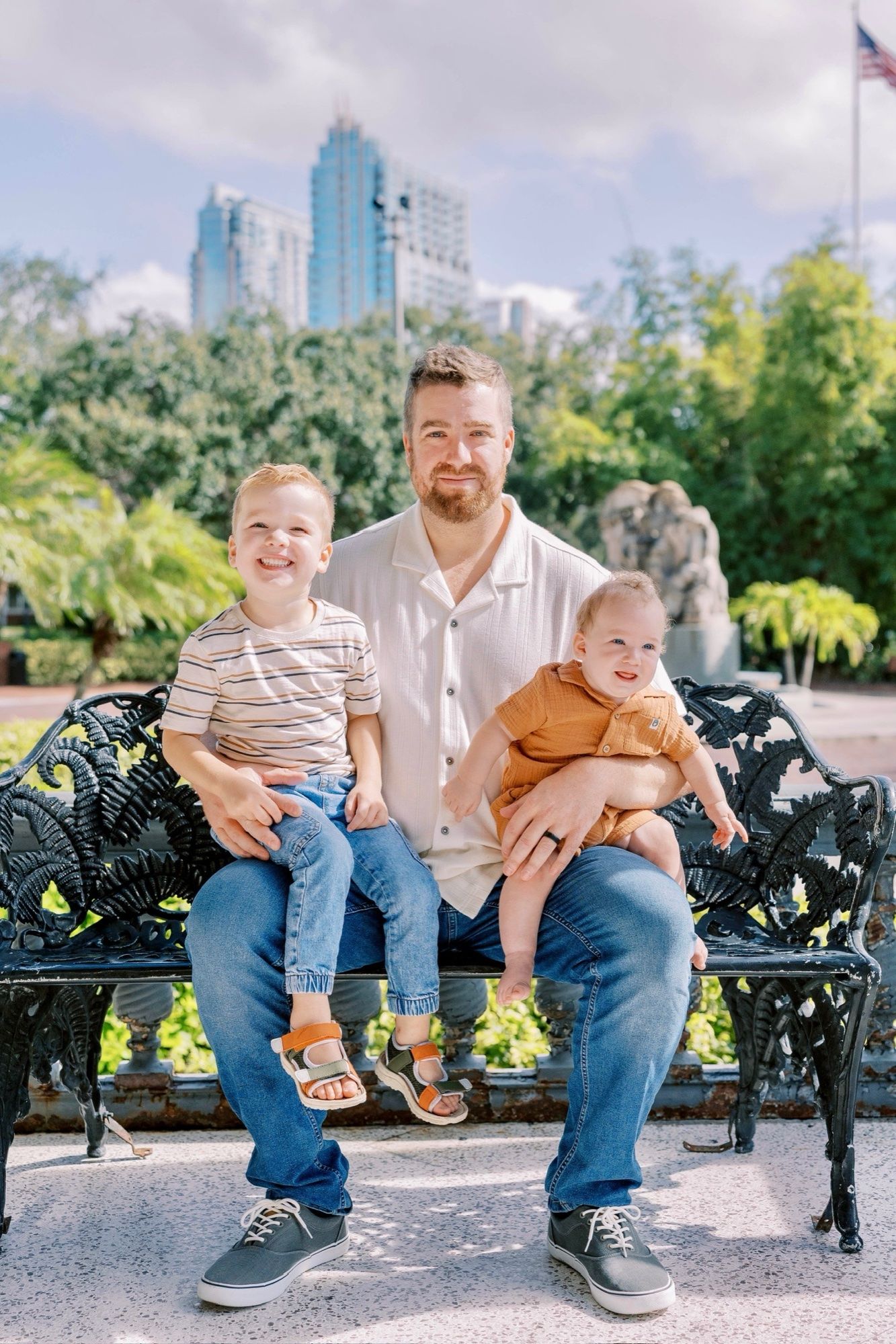 Mike Shanahan on a bench with his two sons, downtown Tampa behind them